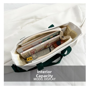 Top view showing the spacious interior of a white canvas tote bag with green straps