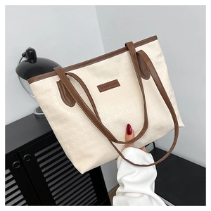 Detailed close-up of textured cream tote bag with brown leather trim and fashion logo