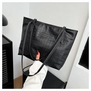 Detail of black tote bag featuring textured houndstooth pattern and fashion label