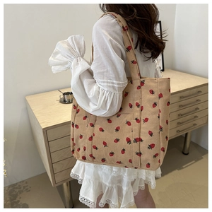 Detail of corduroy tote bag with strawberry print and soft texture on a shoulder strap