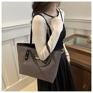 Detail of grey canvas tote bag featuring red heart patterns and long shoulder strap