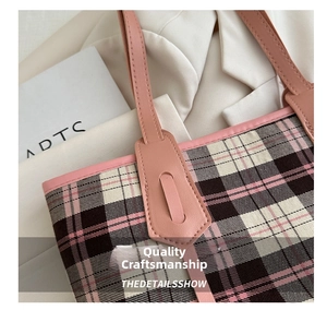 Close-up of pink and brown checkered tote bag with refined leather handle and stitching