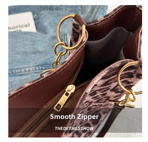 Detail of smooth metal zipper and large golden ring hardware on leopard tote bag