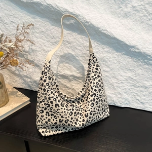 Large leopard print tote bag with cream straps on a dark wooden surface in a chic setting