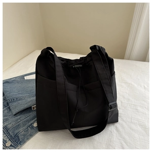 Detail of black large capacity tote bag featuring drawstring closure and side pockets