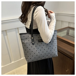 Détail d'un grand sac cabas gris à pois avec des anses en cuir noir à l'épaule