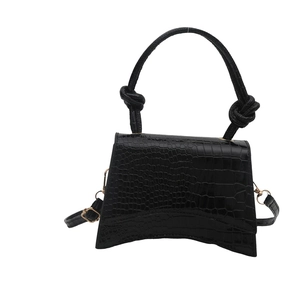 Minimalist black crocodile embossed crossbody bag with curved base and knot handle detail