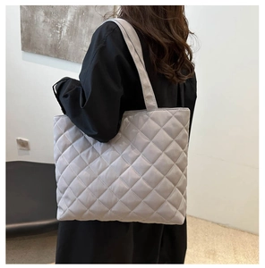 Rear view of a light gray quilted tote bag on a model showing large capacity and scale