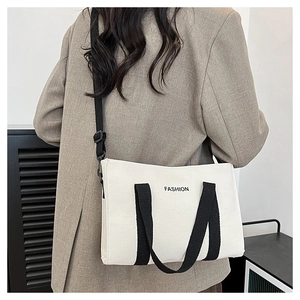 Détail du sac en toile blanche avec logo FASHION et bandoulières noires sur modèle