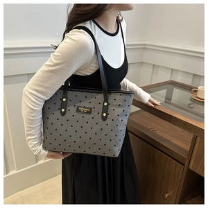Détails du cabas gris à pois montrant les rivets dorés et la plaque de logo de mode