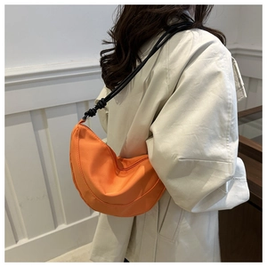 Detail of a bright orange nylon crescent bag with slim black adjustable drawstrings