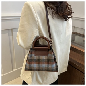 Détail du sac à carreaux montrant le tissu en laine marron, gris et bleu et la poignée ronde