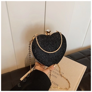 Macro view of black heart-shaped clutch with glitter finish and gold chain strap