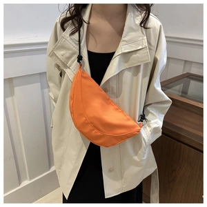 Detail of a bright orange crescent crossbody bag made of waterproof nylon material