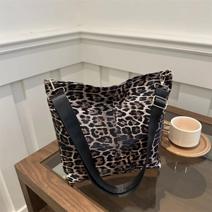 Large leopard print canvas tote bag with black wide shoulder strap on wooden table