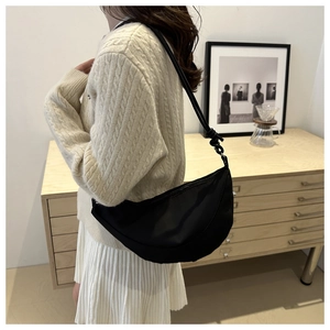 On-body shot of a black minimalist oxford fabric crescent bag with zipper closure
