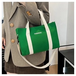 Detail of green canvas tote bag featuring white fashion print and durable handles