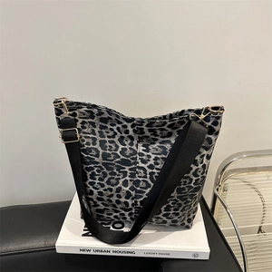 Fashionable leopard print canvas tote bag with wide black strap on a white book decor