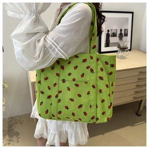 Detail of corduroy tote bag with strawberry print and functional front pocket