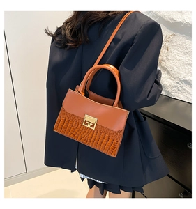 Detail showing caramel brown patchwork leather texture with crocodile pattern and metal lock