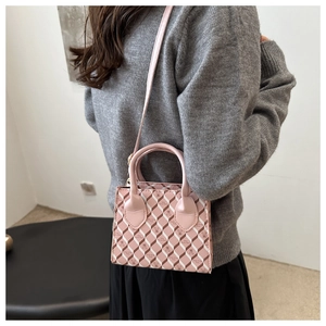 Sac bandoulière rose avec matelassage géométrique et motif ours porté par un mannequin