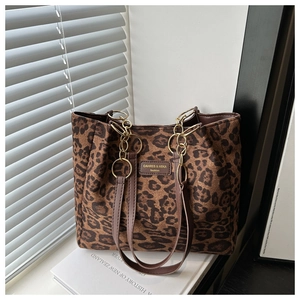Detail of leopard print tote bag featuring gold chain strap and brand label on white stand