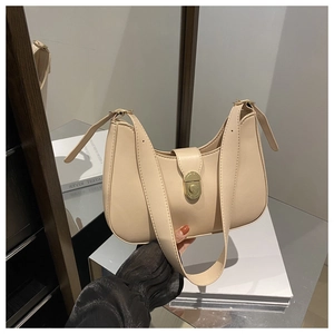 Detail of a beige crescent underarm bag featuring a gold clasp and a wide strap