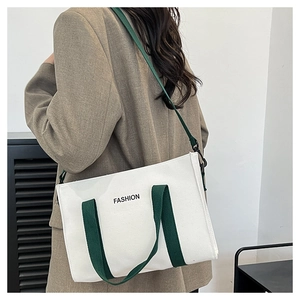 Détail du sac cabas en toile blanche avec anses vertes et lettrage FASHION porté