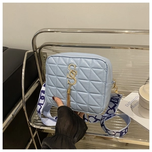Détail du sac bandoulière matelassé bleu clair avec logo S doré et large sangle à motifs