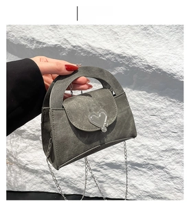 Detail of grey denim mini square bag with silver heart-shaped clasp and metal chain strap
