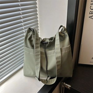 Chic sage green nylon tote bag with drawstring closure and side pockets for daily commute
