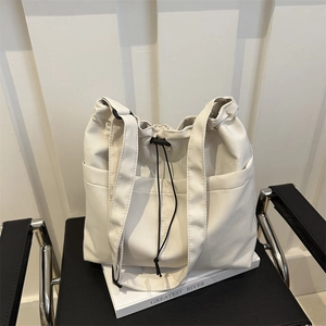 Minimalist cream canvas tote bag with black drawstring closure and adjustable shoulder strap