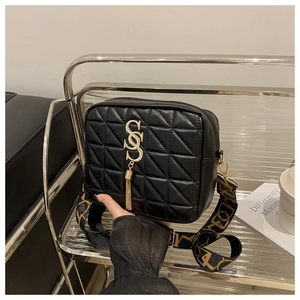 Détail du sac bandoulière matelassé noir avec logo SS doré et franges sur présentoir
