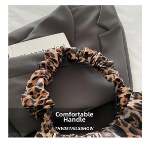 Détail d'un sac à main léopard avec une poignée plissée confortable et design moderne