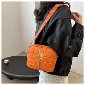 Détail d'un sac bandoulière orange vif avec surpiqûres et gland en métal doré