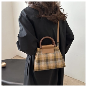 Détail du sac à main vintage à carreaux en laine avec poignées en bois et bandoulière en cuir