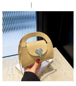 Detail of yellow leather handbag featuring a silver heart-shaped clasp and chain strap
