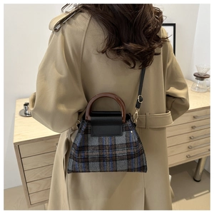 Détail du sac à main à carreaux avec rabat en cuir et poignée ronde sur un trench-coat