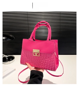 Dettaglio borsa a tracolla rosa con texture coccodrillo e fibbia quadrata dorata