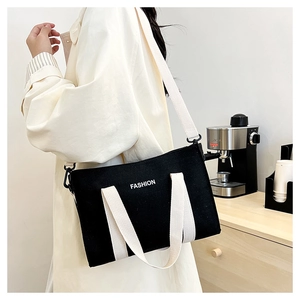 Vue détaillée d'un sac cabas en toile noire avec lettrage blanc et anses en coton