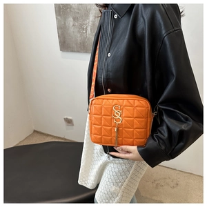 Détail du sac bandoulière matelassé orange avec boucle S dorée et large sangle