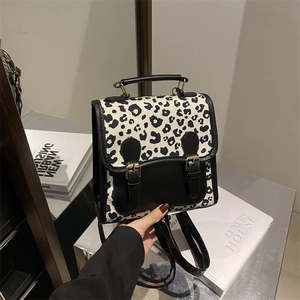 Großer Rucksack mit Leopardenmuster und Lederklappe, von Hand auf Metallfläche gehalten