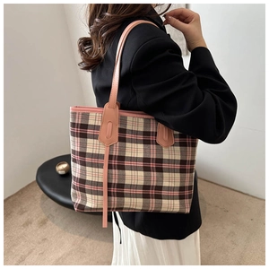 Detail of pink plaid tote bag with side ribbons worn by a model in casual attire