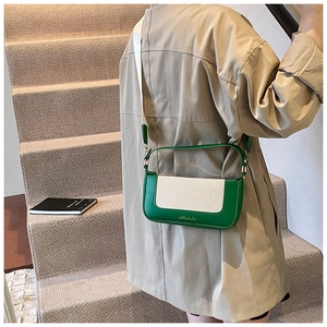 Dettaglio borsa a tracolla patchwork verde e beige con tracolla larga su trench beige