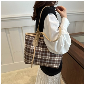 Detail of classic brown and white checkered tote bag with reinforced leather handles