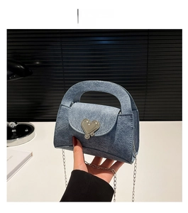 Detail of blue denim textured mini bag with silver heart-shaped lock and chain strap