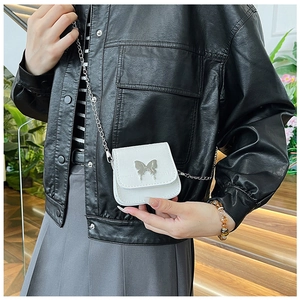 Detail of mini pearl white crossbody bag with crocodile pattern and silver butterfly charm