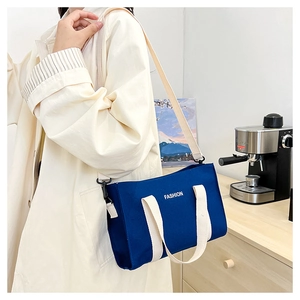 Blue canvas tote bag with FASHION print shown on model wearing a beige trench coat