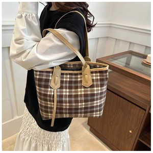 Detail of elegant plaid tote bag with premium cream leather handles and vintage texture