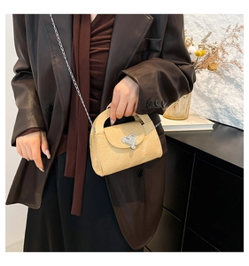 Detail of beige textured crossbody bag with silver heart clasp and chain strap